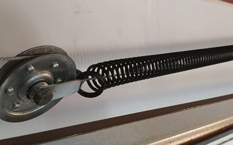 Garage door extension spring running along the horizontal side track